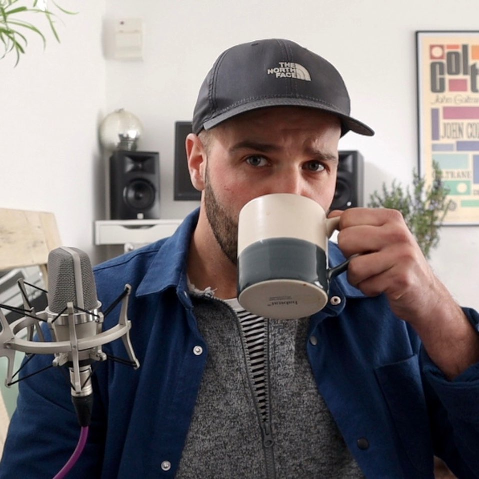 Men with a black cap and white and blue coffee mug looking into the camera